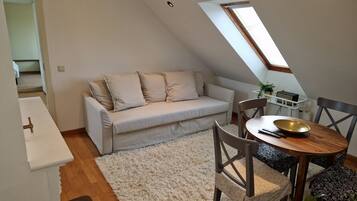 Un loft acogedor con sofá, una mesa de comedor y una pequeña cocina.