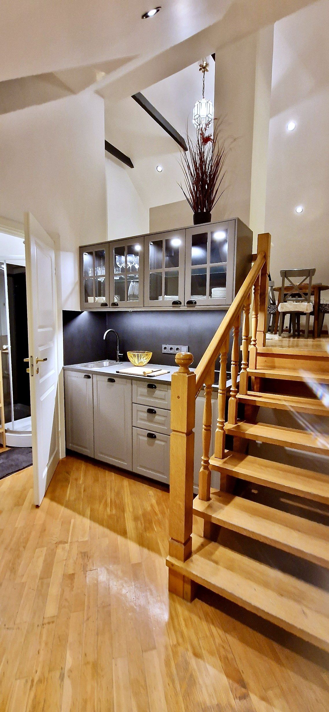 Cozinha moderna com escada de madeira, área de jantar e vista para a sala de estar.