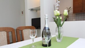 A dining table with a bottle of Martini wine, two empty wine glasses, and a vase with white tulips. - Apartment Irena (Pula)