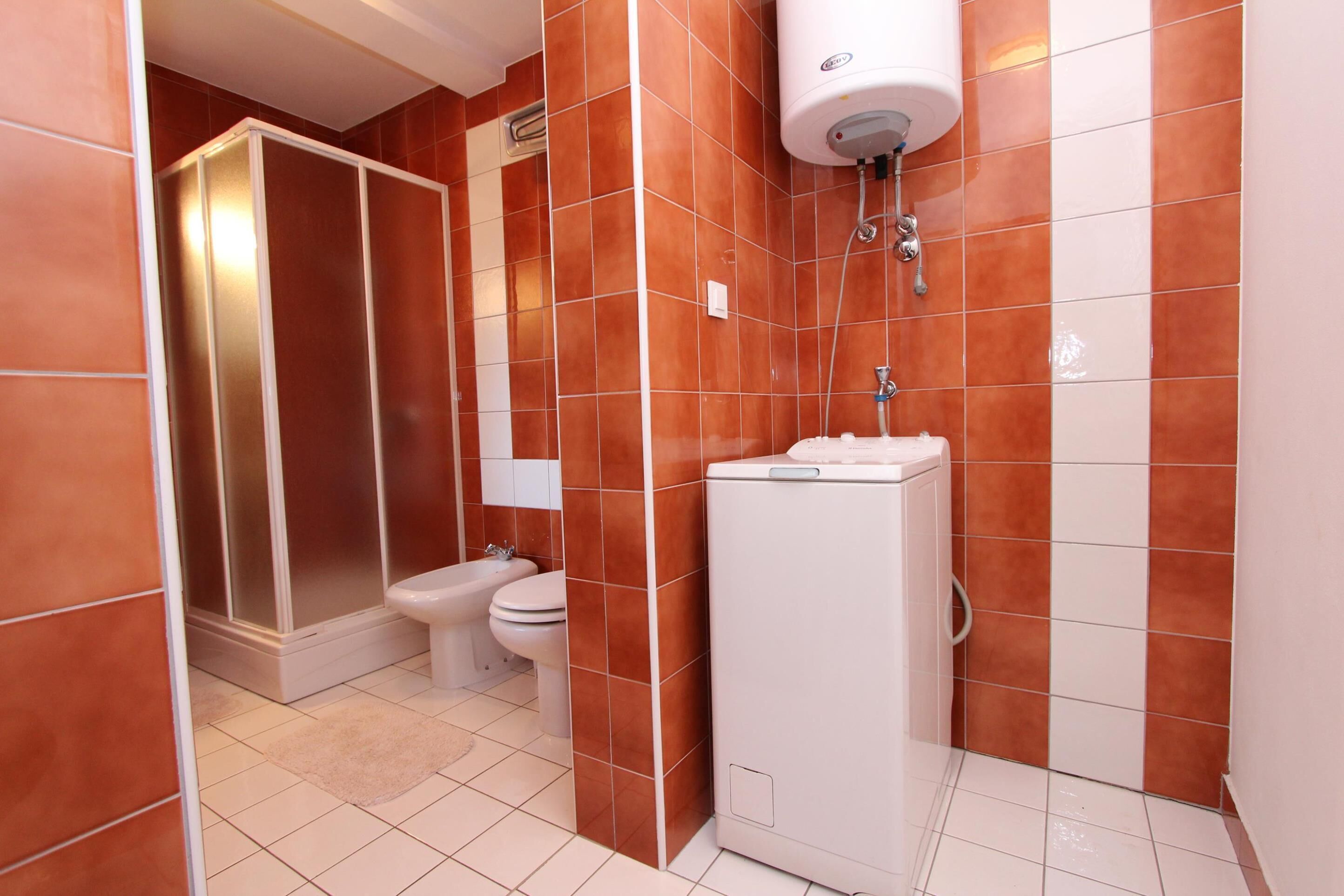 Een badkamer met een douche, toilet en wastafel.