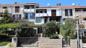 A row of modern two-story houses with satellite dishes, a stone wall gate, and a pergola. - Apartment Irena (Pula)