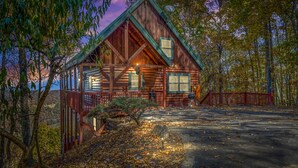 A log cabin with a porch, a red fence, and a view of the surrounding forest. - Endless VIEWS! 3 decks - cozy - Private-with Game Room, Hot Tub, Arcade (Pigeon Forge)