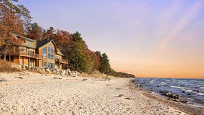 A beachfront property with a large house featuring multiple balconies and a stone foundation.