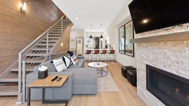 A modern living room with a grey sectional sofa, a small coffee table, a fireplace, and a kitchen area in the background. - Private Rooftop Balcony w/ Hot Tub & Panoramic Mountain Views, Close to Shops (Silverthorne)