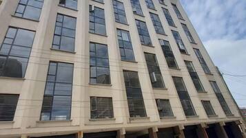 Un edificio de varios pisos con ventanas amplias y contraventanas cerradas al nivel de la calle.