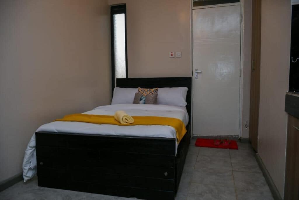 A bedroom with a bed, a door, and a small window.