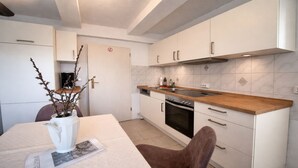 Una cocina moderna con armarios blancos, encimera de madera y horno empotrado.