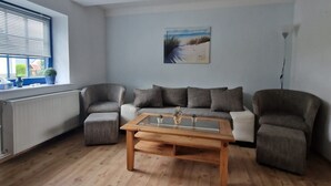 Amplia sala de estar con una mesa de centro de madera, sofás grises y un cuadro en la pared.