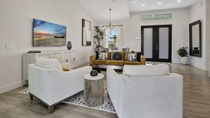 A modern living room with a sofa set, a coffee table, and a painting of a sunset. - Golf Course Views, Private Pool & Pet-Friendly (Bonita Springs)