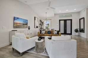 A modern living room with a sofa set, a coffee table, and a painting of a sunset. - Golf Course Views, Private Pool & Pet-Friendly (Bonita Springs)