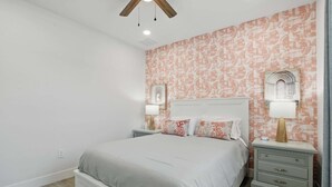 A bedroom with a large bed, two bedside tables with lamps, a ceiling fan, and patterned wallpaper. - Golf Course Views, Private Pool & Pet-Friendly (Bonita Springs)