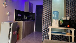 A compact kitchen with a refrigerator, microwave, and a water dispenser on a small table. - Lux Suites Convertible Studios Embakasi (Nairobi)