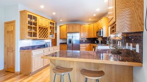 Una cocina moderna con armarios de madera, un refrigerador de acero inoxidable y una encimera de granito.