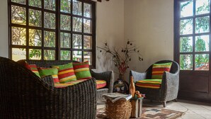 A room with wicker furniture, large windows, and a tiled floor. - Casa Bugambilia

 (Bejuco)