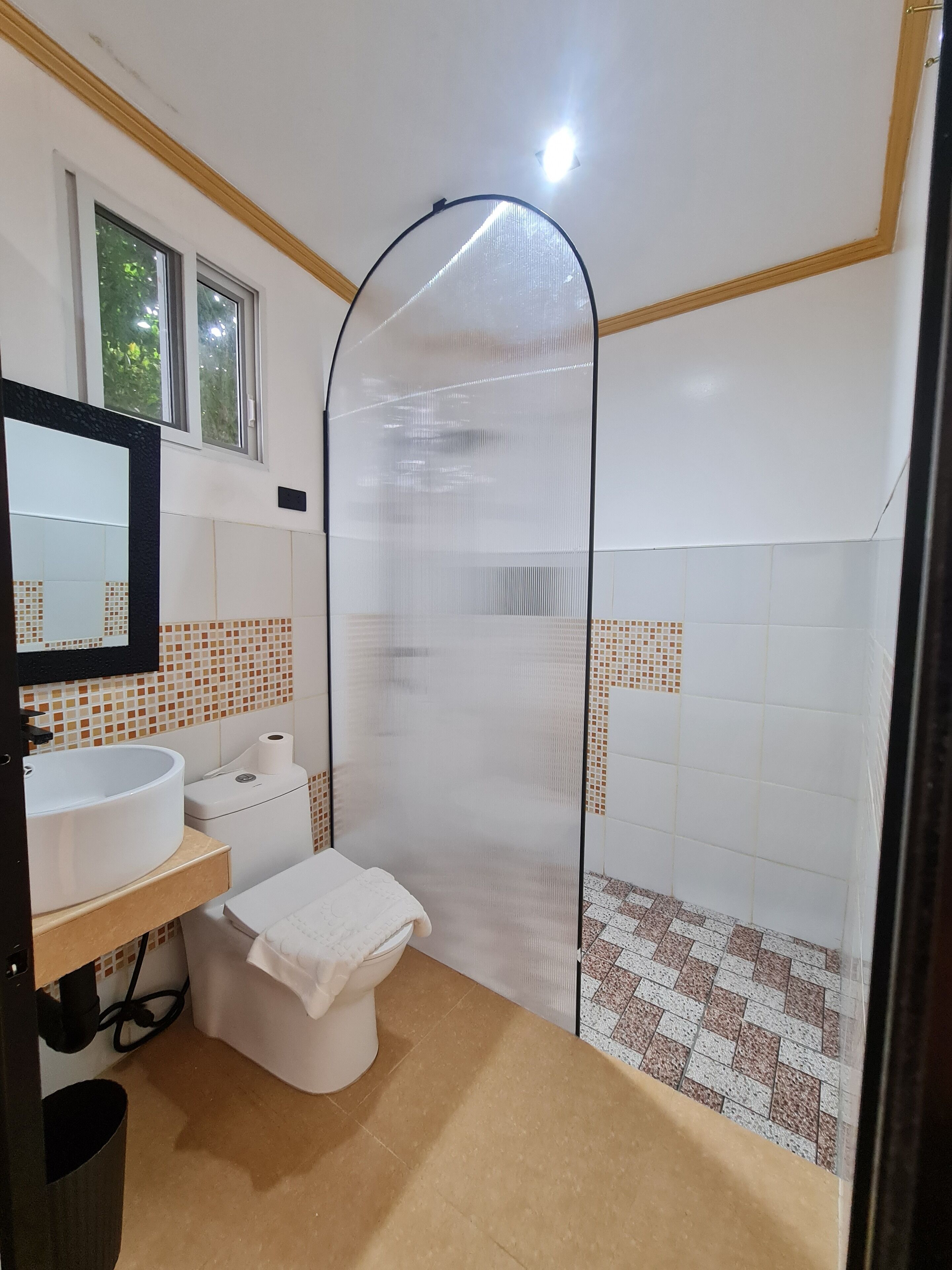 A bathroom with a white sink, toilet, and shower enclosure.