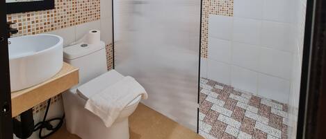 A bathroom with a white sink, toilet, and shower enclosure.