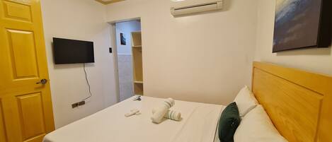 Habitación de hotel con cama, televisión, aire acondicionado y un cuadro en la pared.