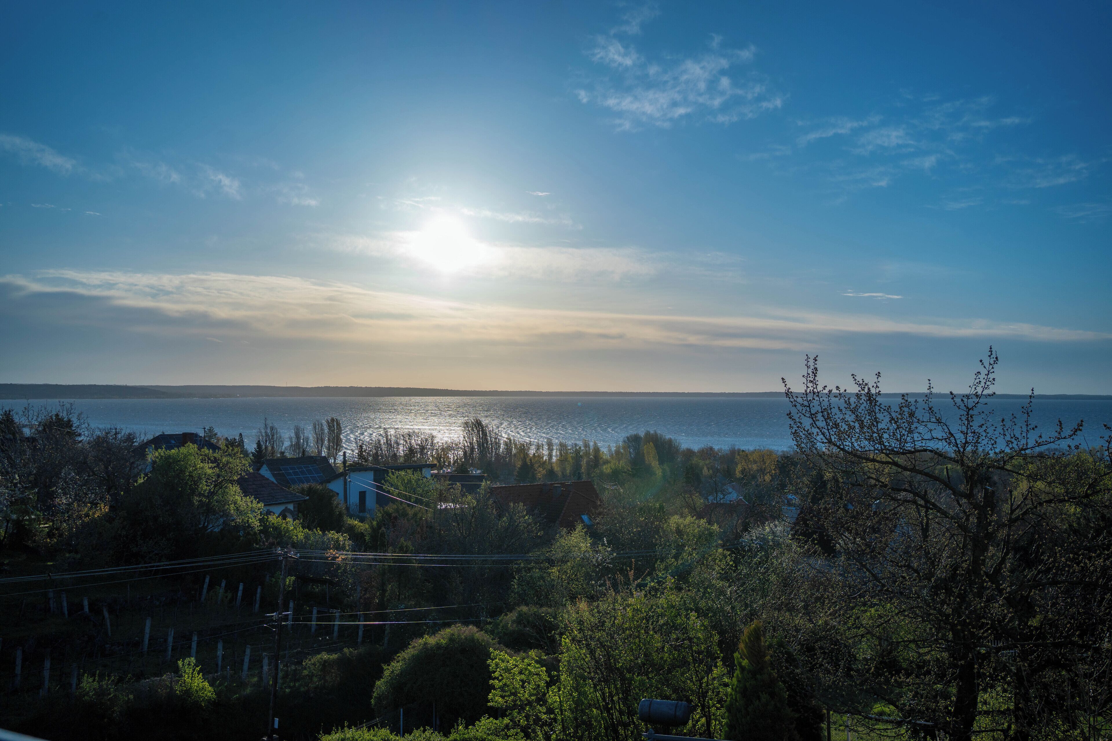 A coastal landscape with a clear sky, a body of water, and residential buildings.