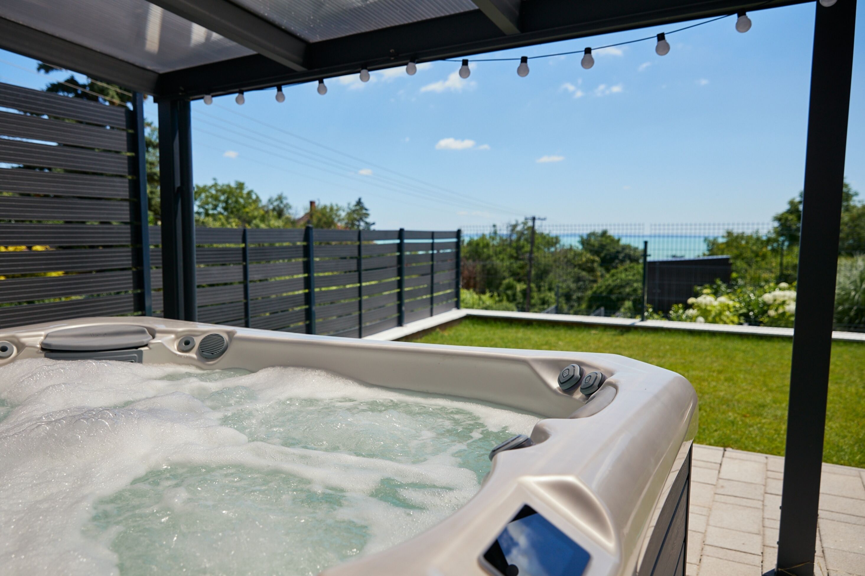 Uma banheira de hidromassagem com vista para um jardim e uma cerca ao fundo.