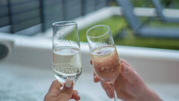 Two people holding champagne glasses over a hot tub.