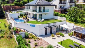 A modern two-story house with a pool, a covered patio, and a well-maintained garden. - Lake Spirit Boutique Apartments (Balatonalmadi)