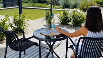 Eine Terrasse mit einem runden Tisch, zwei Stühlen, einer Flasche und einer Pflanze.