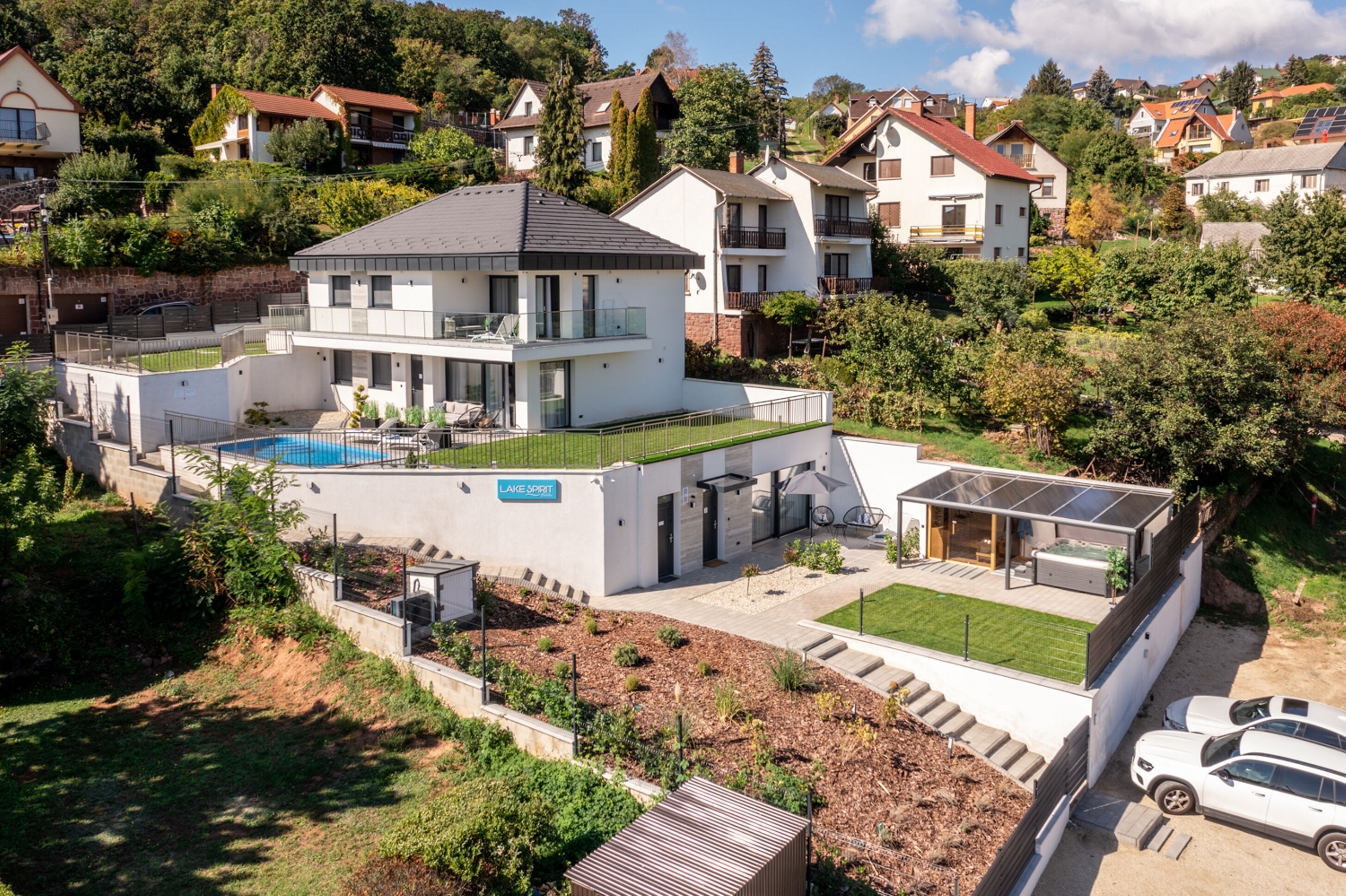 A modern two-story house with a swimming pool, a covered patio, and a well-maintained garden.