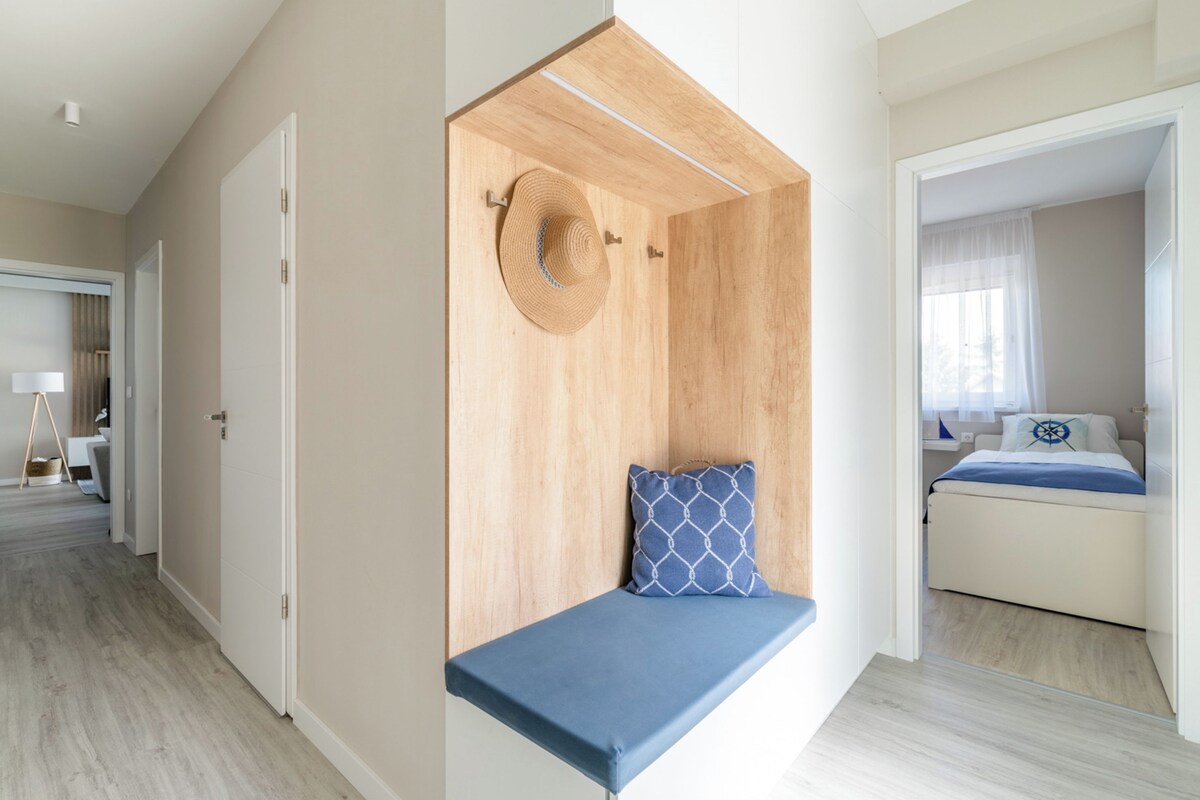 A modern bedroom with a built-in bench, a bed with a blue and white patterned pillow, and a wooden accent wall.