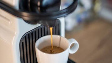 Une machine à café verse du café dans une tasse blanche posée sur un plateau noir.