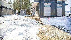 A modern two-story building with a metal exterior and large windows, surrounded by snow and trees. - Brooklyn Circle Loft — Newly Built 1BR + Loft, Hilltop, Walk Downtown (Leadville)
