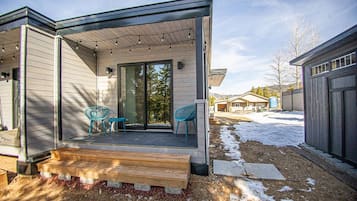 Une maison moderne dotée d’un porche couvert, d’une porte-fenêtre coulissante et d’un petit espace de détente extérieur.