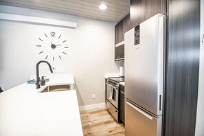 Une cuisine moderne équipée d’un réfrigérateur, d’un four et d’un évier en acier inoxydable.