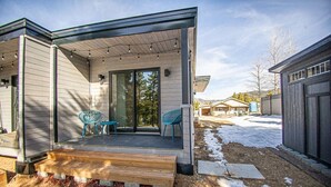 A modern house with a covered porch, a sliding glass door, and a small outdoor seating area. - Brooklyn Circle Loft — Newly Built 1BR + Loft, Hilltop, Walk Downtown (Leadville)