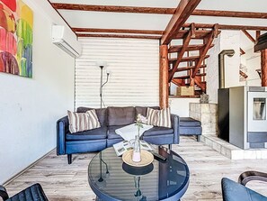 A cozy living area with a blue sofa, a glass coffee table, and a fireplace.