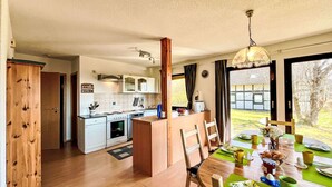 A compact kitchen with white cabinets, a central island, and a dining area with a green table. - Beautiful apartment in villa for 4 guests with WIFI, TV and pets allowed (Bad Wildungen)
