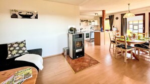 A cozy living room with a sofa, a dining table with chairs, a kitchen area with appliances, and a wooden floor. - Beautiful apartment in villa for 4 guests with WIFI, TV and pets allowed (Bad Wildungen)