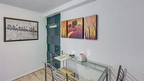 A dining area with a glass table, chairs, and a framed picture on the wall. - Pet-friendly Great Neck Home ~ 1 Mi to Kings Point (Great Neck)
