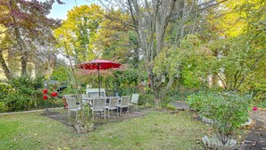 A patio with a table and chairs, surrounded by trees and a red umbrella. - Pet-friendly Great Neck Home ~ 1 Mi to Kings Point (Great Neck)