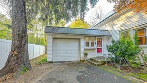 A detached garage with a white door, a small porch with a red door, and a potted plant on the steps. - Pet-friendly Great Neck Home ~ 1 Mi to Kings Point (Great Neck)