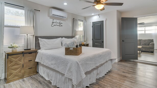 Une chambre à coucher avec un lit, une table de chevet, une lampe et un ventilateur de plafond.