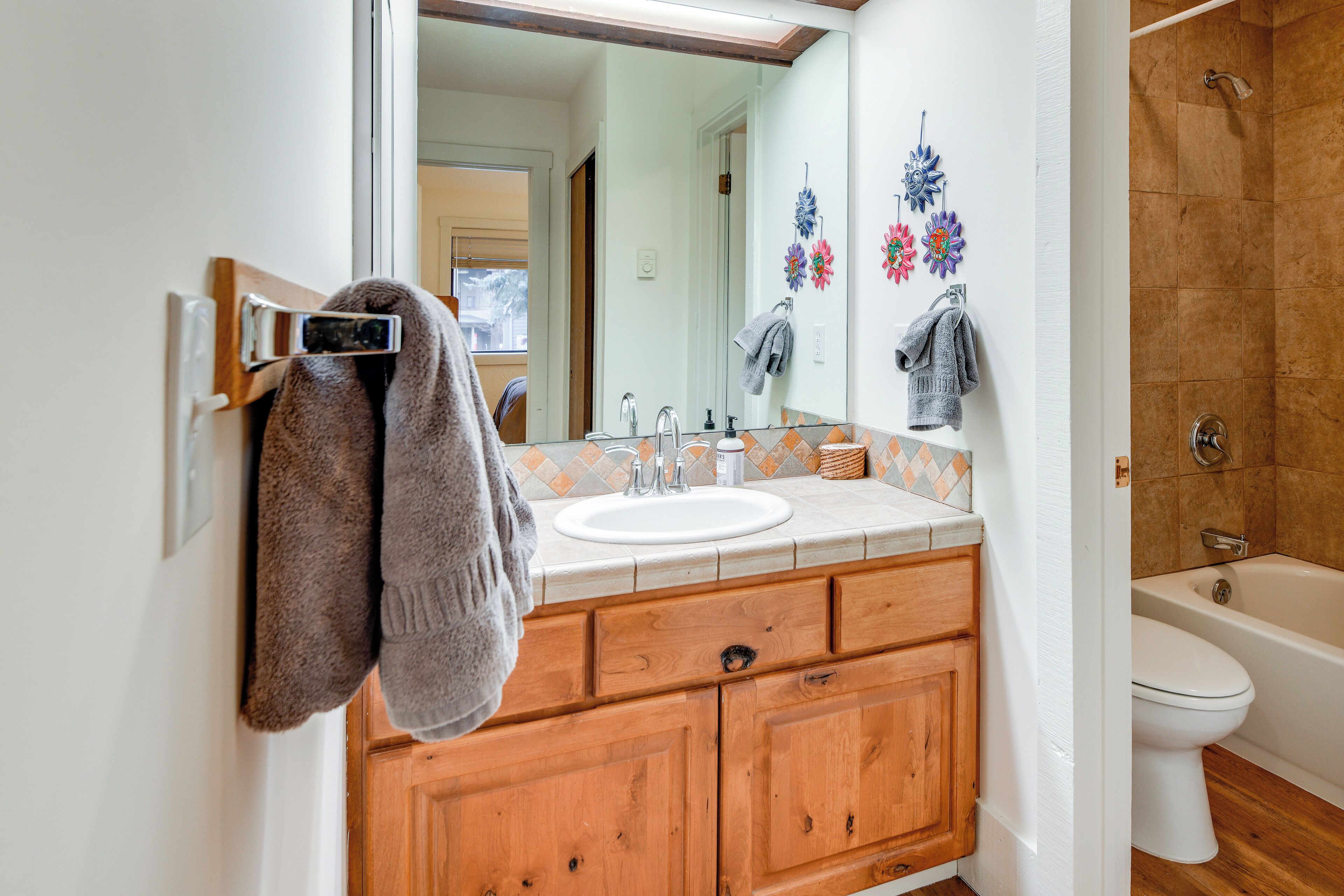 A bathroom with a wooden vanity, a white sink, a mirror, and a shower area.