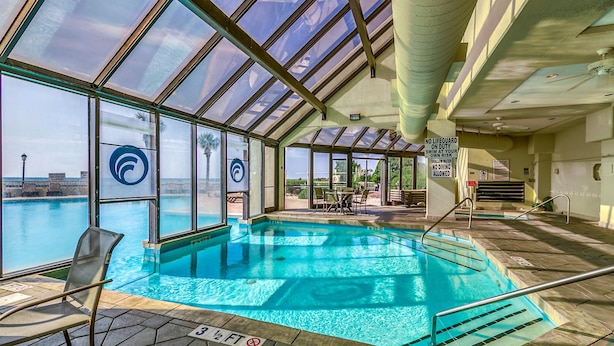 Una piscina interior con paredes de vidrio transparente, un letrero de salvavidas y vistas a la ciudad.