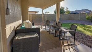 Zona de porxo coberta amb mobles de vimetla, un ventilador de sostre i vista a un jardí.