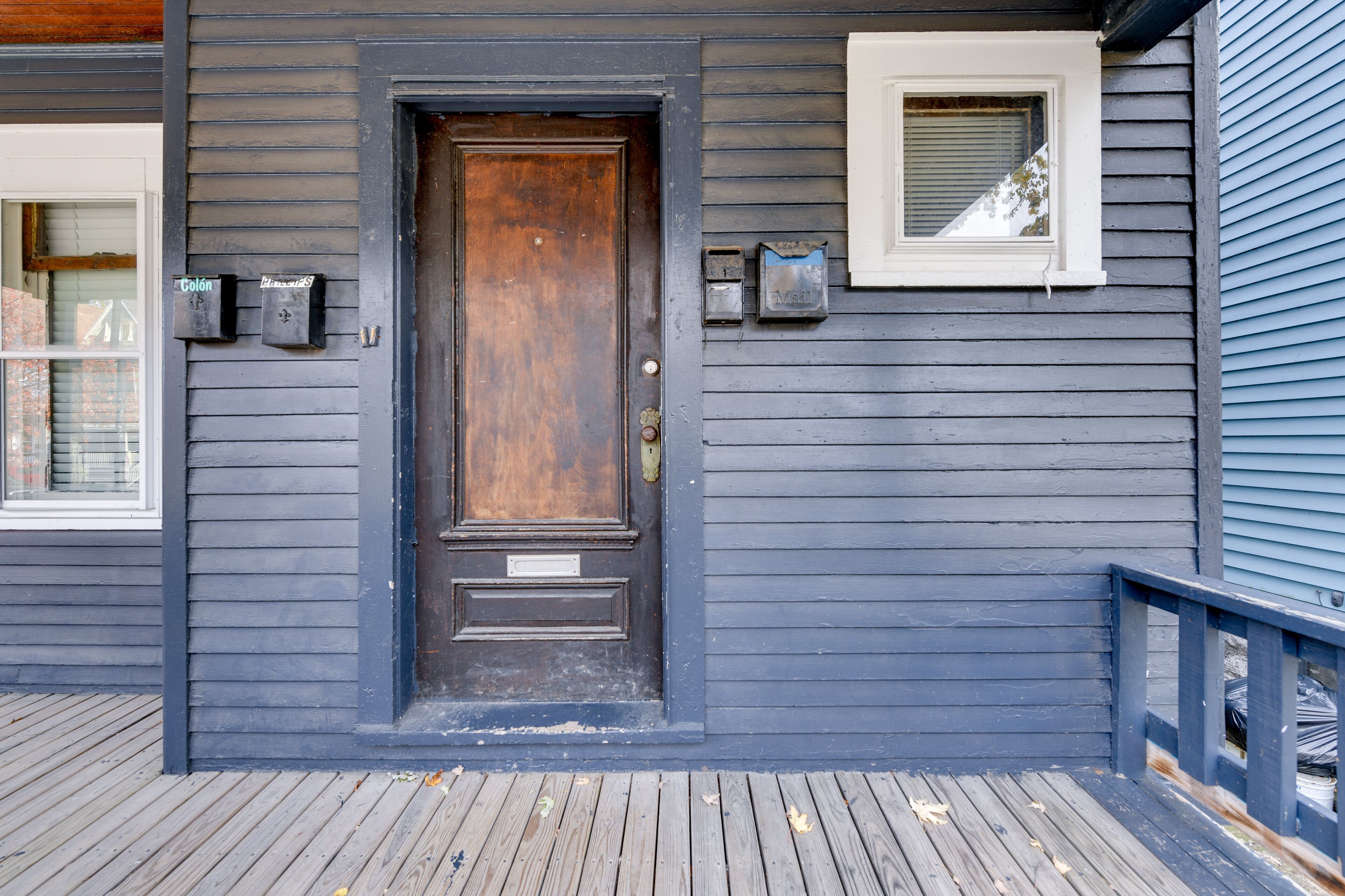 A wooden door with a metal handle, a mailbox, and a window with a white frame.