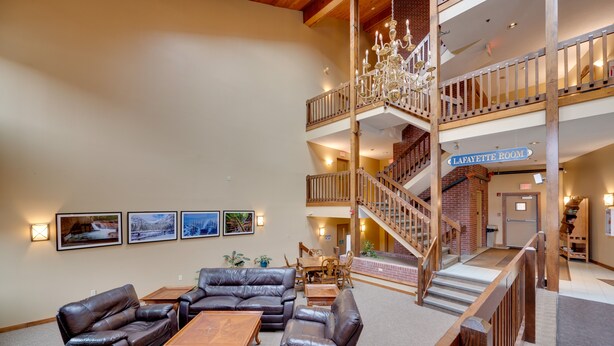 A spacious lobby with leather sofas, wooden tables, and a chandelier. A sign indicates the Lafayette Room.