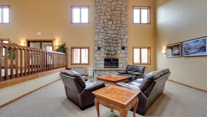 A lobby with a stone fireplace, leather sofas, and a wooden coffee table.