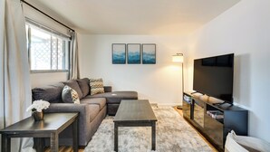 Ein modernes Wohnzimmer mit einer Couch, einem Couchtisch, einer TV-Konsole und einem Wand-Fernseher.