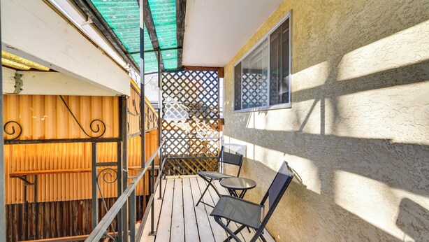 Ein Balkon mit Holzboden, Metallstühlen und einem kleinen Tisch.