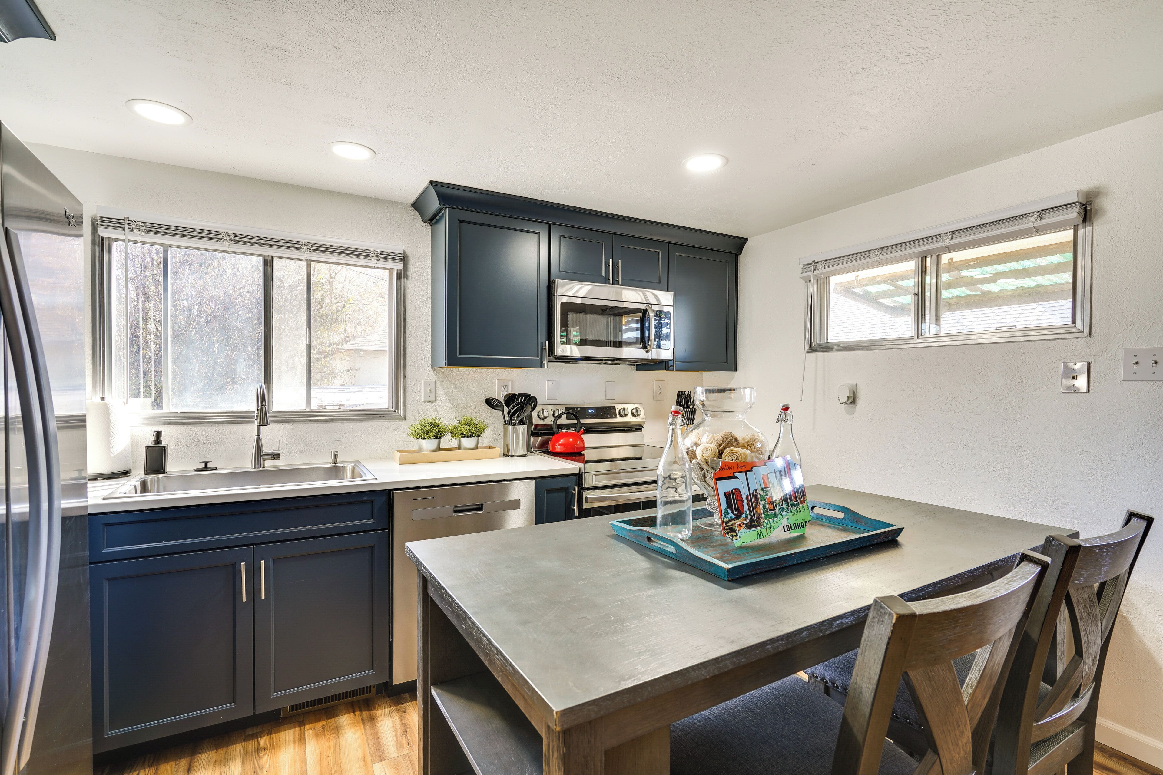 A modern kitchen with dark cabinets, stainless steel appliances, and a dining area with a wooden table and chairs.