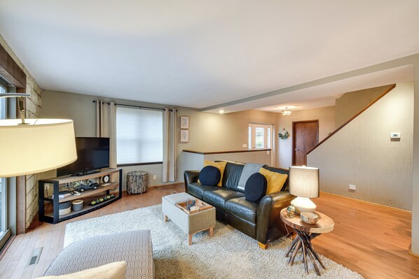 A modern living room with a leather sofa, a coffee table, and a TV on a stand. - Large Home w/ Game Room, 4 Mi to Mississippi River (Bettendorf)